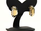 une paire de boucles d'oreilles en or et diamants posée sur un socle noir, sur fond blanc