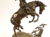 statue représentant un homme à cheval avec un chien sur un rocher