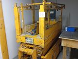 a yellow forklift sitting in a room next to a table