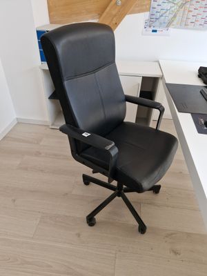 une chaise de bureau noire assise devant un bureau blanc