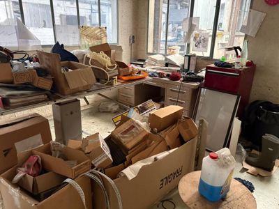 une pièce où il y a beaucoup de cartons et d'autres objets par terre