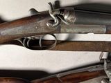 two old guns are displayed on a table with a shadow on the wall