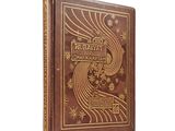an old book with a golden cover sitting on top of a white surface