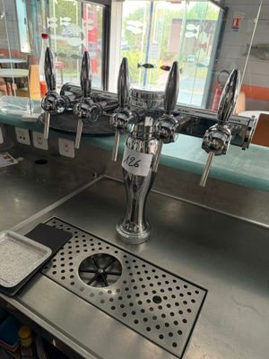 a metal counter with a bunch of beer taps on it