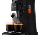 a coffee maker with two cups of coffee in front of it