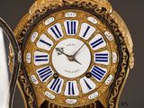 a gold clock with blue and white roman numerals on it