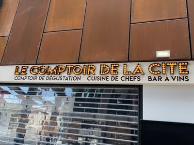 une enseigne sur le mur d'un immeuble indiquant « Le Comptoir de la Cité »