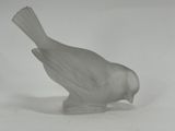 a glass bird that is sitting on a white surface