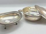two silver plated dishes with lids and handles on a white surface