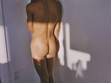 a naked man standing in front of a wall with a picture on the wall