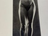 an old black and white photo of a nude woman standing in front of a black background