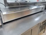 stainless steel counter top in a commercial kitchen with a microwave and oven