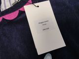 a blue sweater with a pink flower on it and a white tag on it