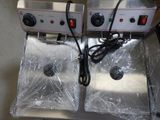 two electric fryers sitting on top of a counter covered in plastic