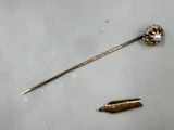an image of a gold pin and a bullet on a white surface