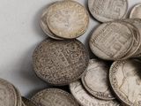 a pile of old silver coins on a white surface
