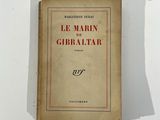 un vieux livre posé sur une table à côté d'un mur blanc