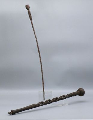 sculpture représentant un bâton d'où sort une longue tige sur le côté