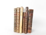 several old books are stacked on top of each other on a white surface