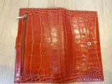 an orange leather wallet with a zipper on top of it