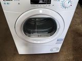 une machine à laver blanche dans un garage, avec un objet rouge posé par terre