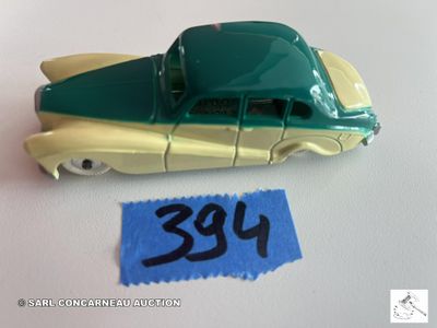 une petite voiture jouet verte et jaune sur laquelle est accrochée une étiquette de prix