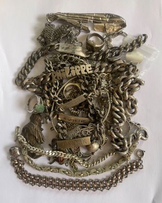 a pile of silver jewelry on a white surface