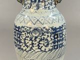 un grand vase bleu et blanc posé sur un socle en bois