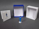 a small figurine of a man in a blue suit next to a box