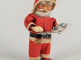 une figurine représentant le Père Noël en train de lire un livre