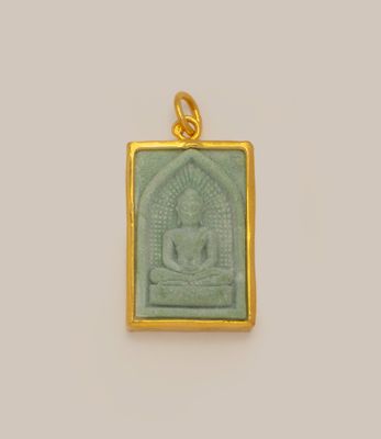 un gros plan d'un pendentif représentant un Bouddha doré et vert sur fond blanc