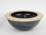 a black and blue bowl sitting on a white surface
