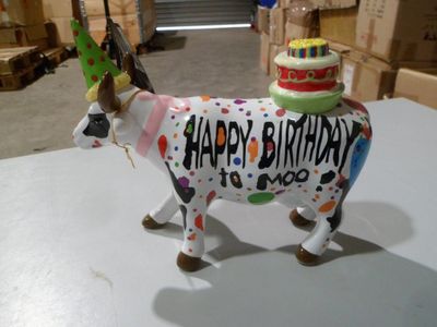 une statue de vache surmontée d'un gâteau d'anniversaire