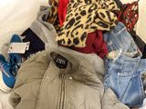 a pile of clothes sitting on top of a bed next to a pair of shoes