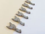 several silver metal birds are lined up on a white and yellow surface