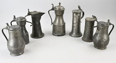 six objets en fer-blanc sont disposés en cercle sur une surface blanche