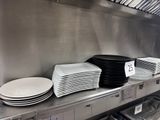 Plusieurs assiettes sont empilées sur une étagère métallique dans une cuisine