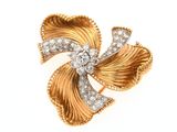 un gros plan sur une broche en forme de nœud, en or et diamants