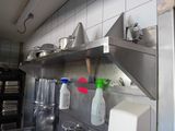 a kitchen with a sink and a metal shelf with pots and pans on it