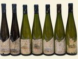 six bouteilles de vin posées les unes à côté des autres sur une surface blanche