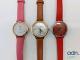 three different colored watches sitting next to each other on a white surface