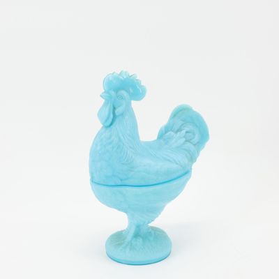 poulet en verre bleu sur un socle, sur fond blanc