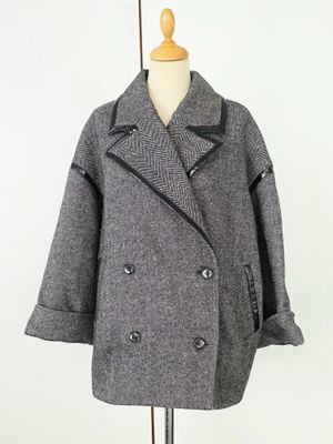 un manteau gris clair posé sur un mannequin, devant un fond blanc
