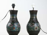 pair of black vases with floral designs on them sitting on a white surface