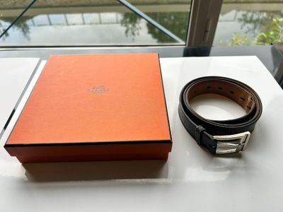 une boîte orange avec une ceinture noire et une boîte marron avec une boucle argentée