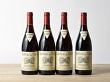 quatre bouteilles de vin sont posées sur une table en bois