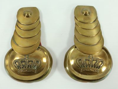 une paire de bougies en laiton ornées de couronnes, posées sur une surface blanche