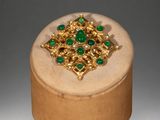 an image of a wooden box with a gold and green broochet