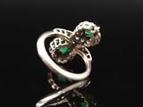 a close up of a silver ring with green stones