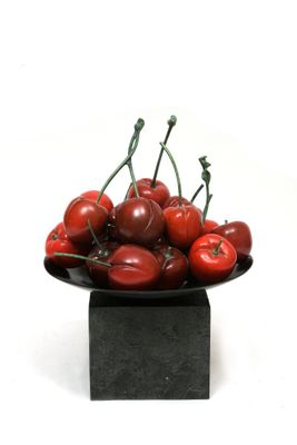 a bowl of cherries sitting on a black plate